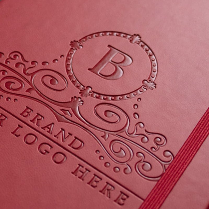 Debossed logo on a red branded notebook